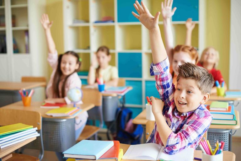 Eager young students raising their hands in a classroom