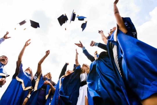 Young graduates tossing caps in the air