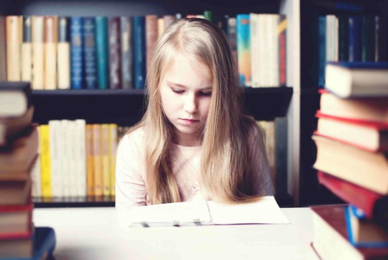 Young girl sitting at a table reading