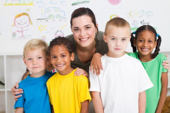 Female teacher smiling with young children in a classroom