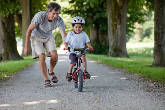 A father teaching his young son how to ride a bike