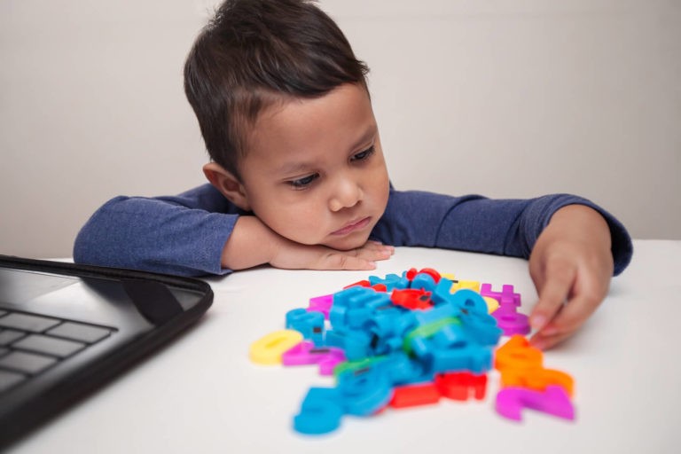 Young boy looking defeated while staring at some plastic numbers.