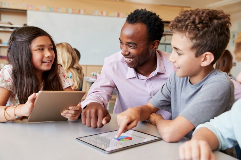 Young teacher talking to students using a tablet.