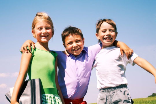 A group of young happy kids with their arms around each other