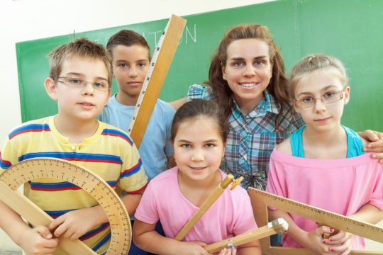 Female teacher and a group of young students holding various measuring tools