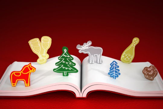 Open book with holiday shapes on the pages on a read background.