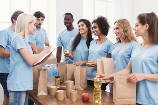 Group of older students packing bags of food for a food drive.