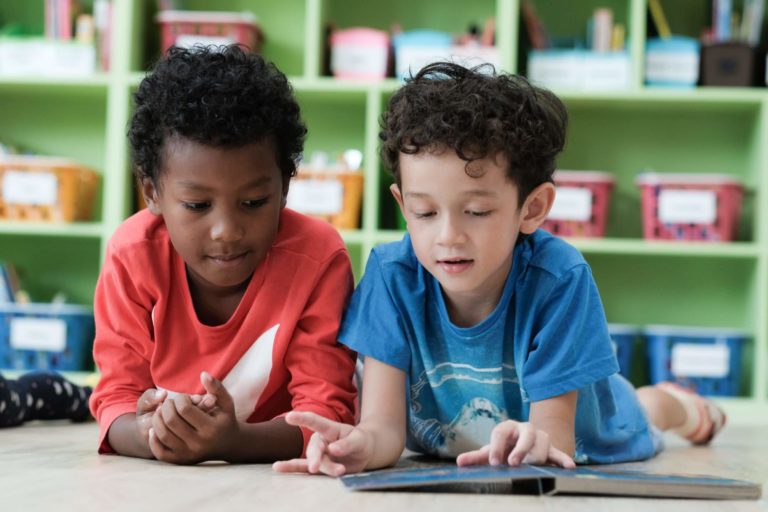 Two young boys reading a book together in their elementary classroom.