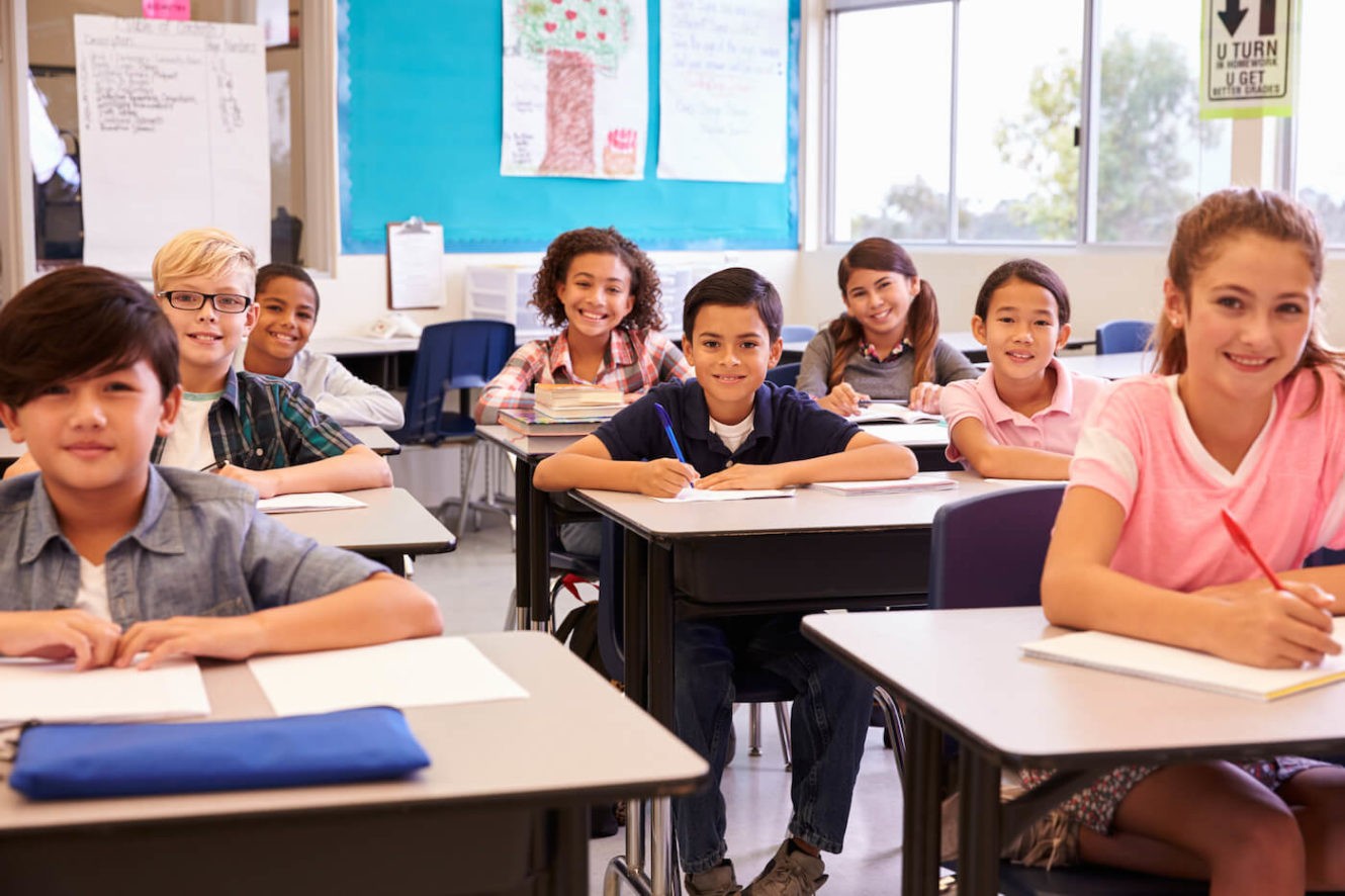 A group of smiling young students in a classroom