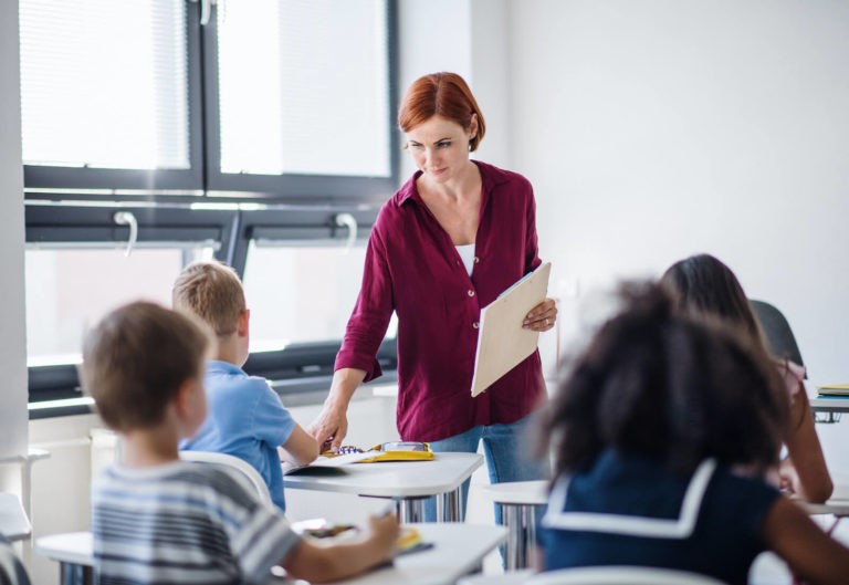 Teacher walking around her classroom full of young students.