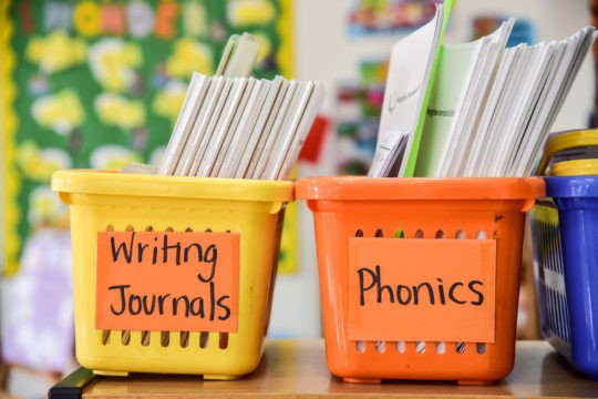 Labeled bins of papers in a classroom.