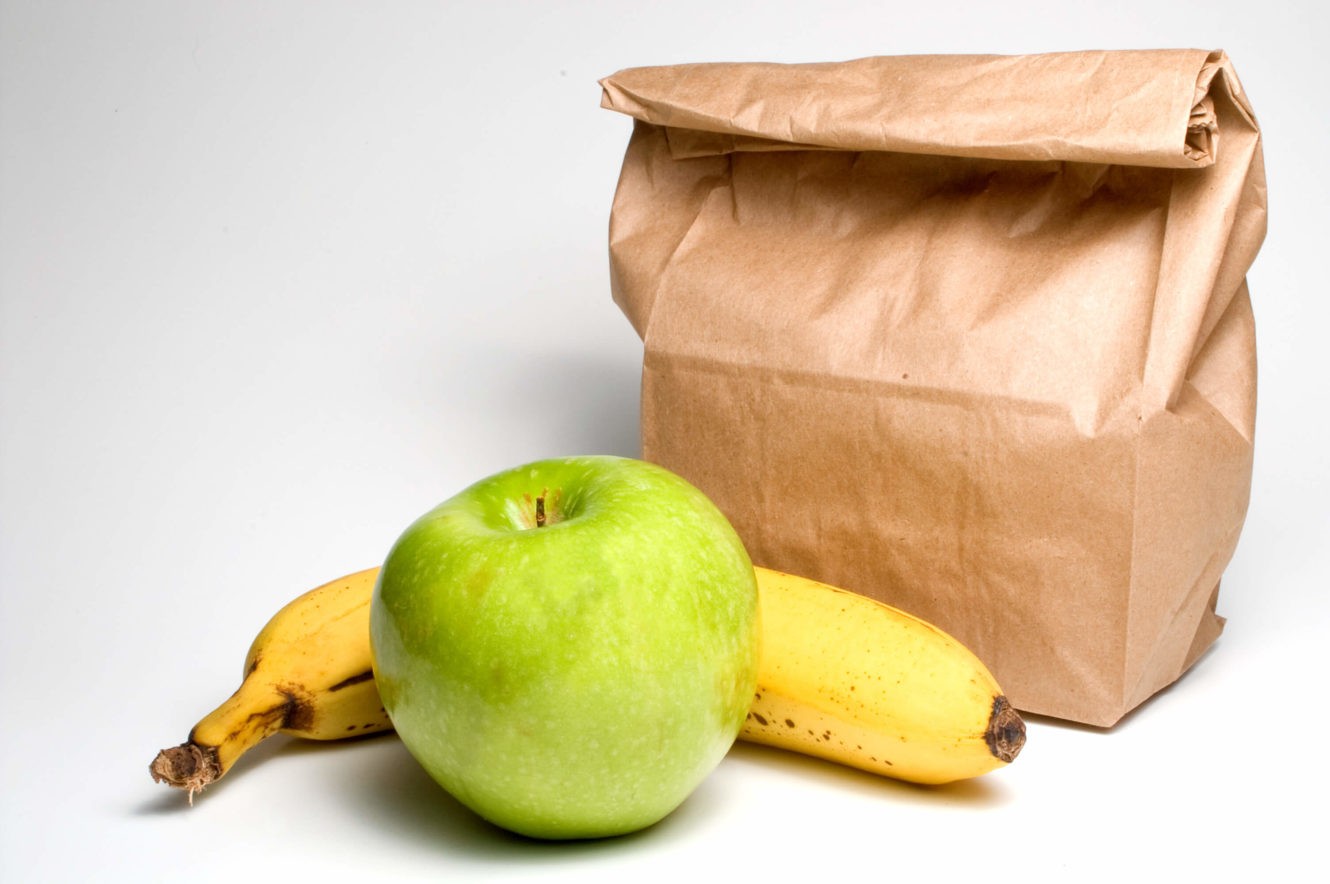 a banana and apple sitting next to a brown paper bag lunch