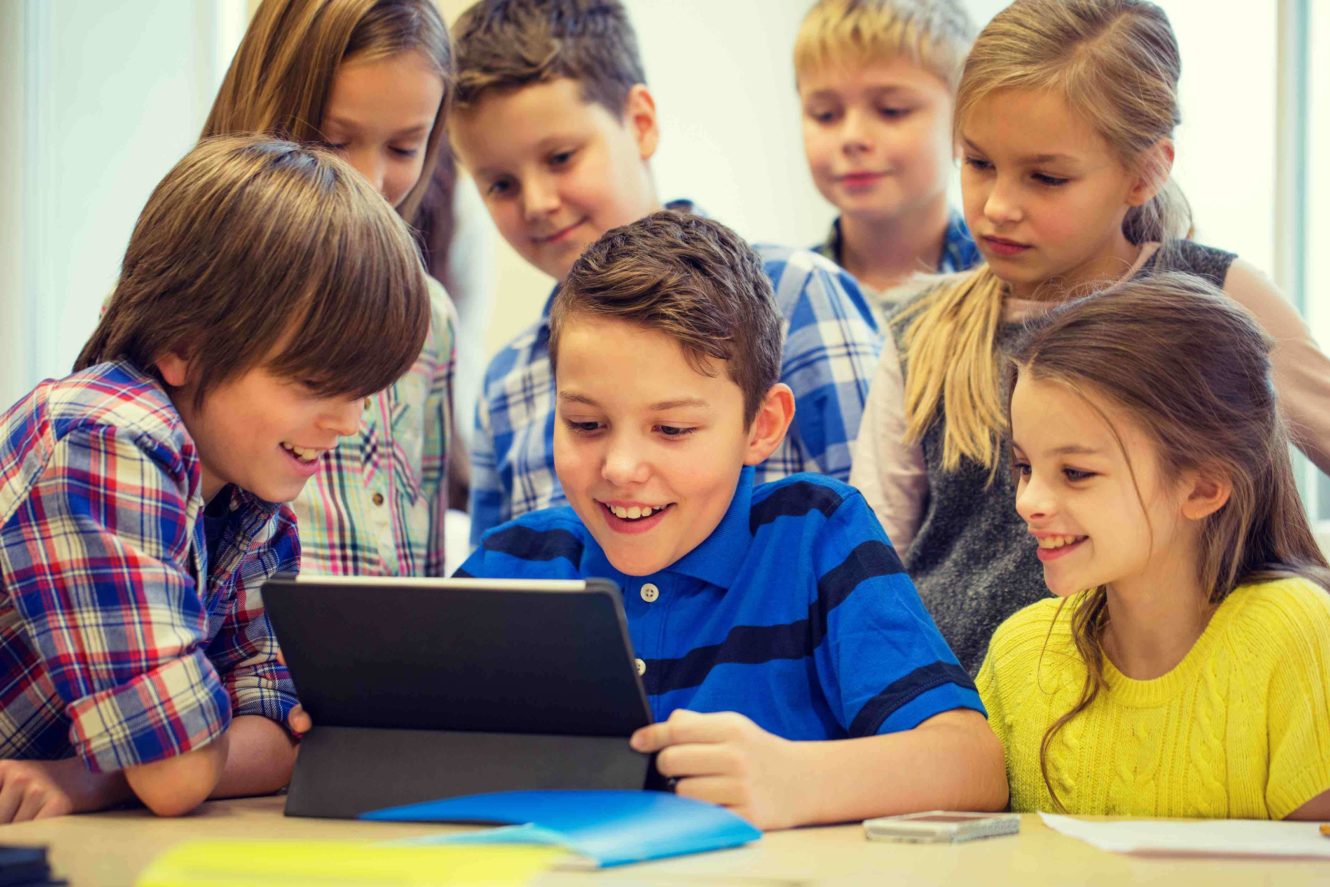 A group of young students gathered around a tablet