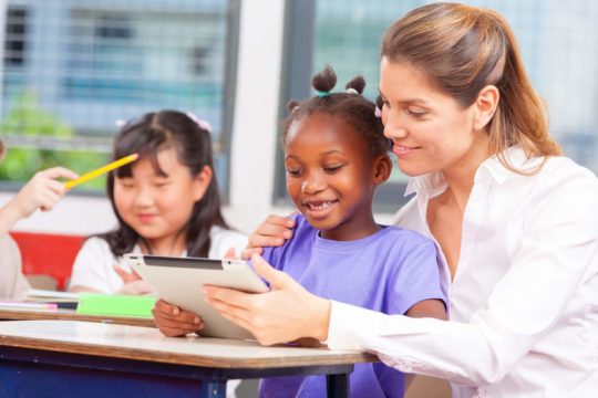 Young student and teacher in a classroom with a tablet