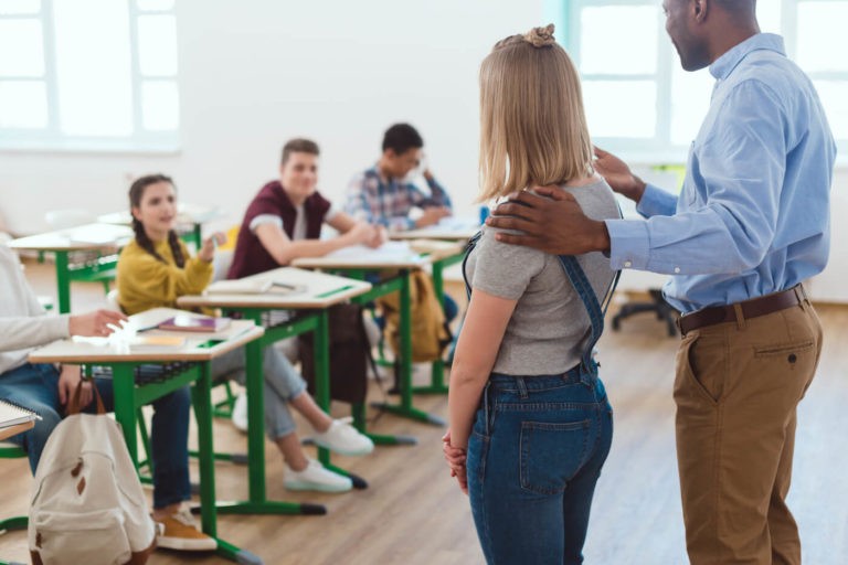 A teacher introducing a new student to a classroom of students.