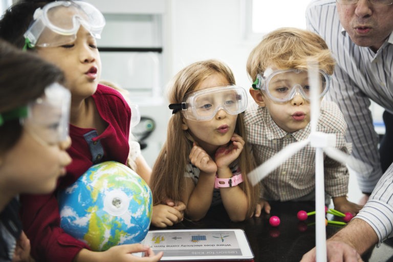 Young students working on a windmill science experiment with their teacher.