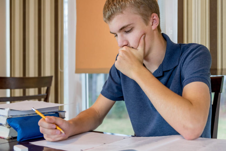 High school students sitting at a table and writing on paper.