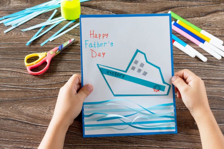 A kid making a Father’s Day craft project whie sitting at a table.