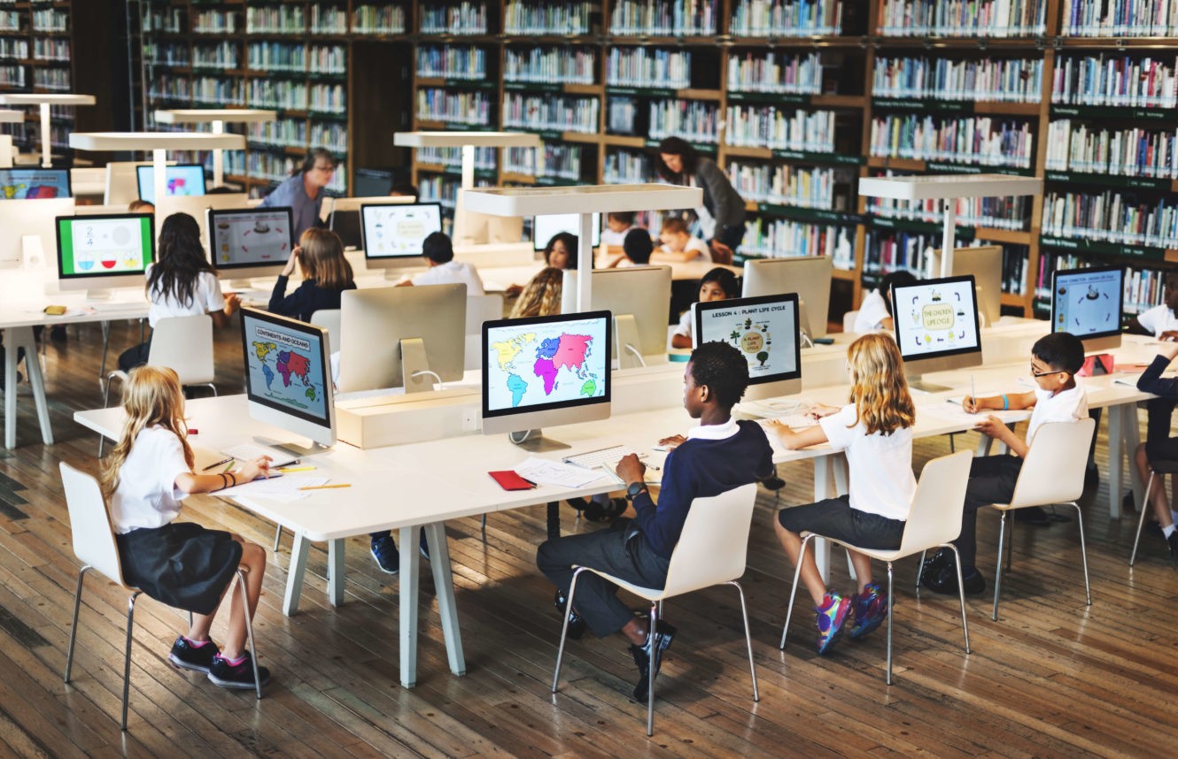 Young students in a computer lab looking at maps