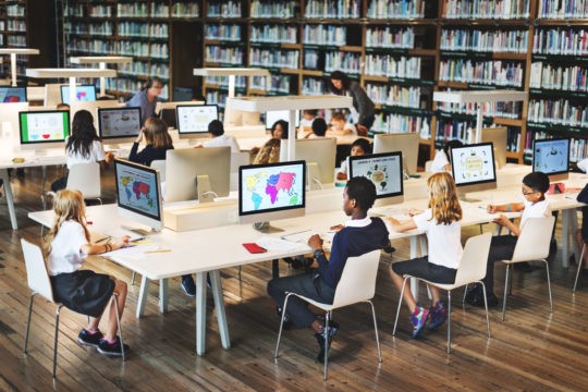 Young students in a computer lab looking at maps