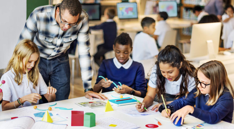 Group of young students sitting a table using manipulatives.