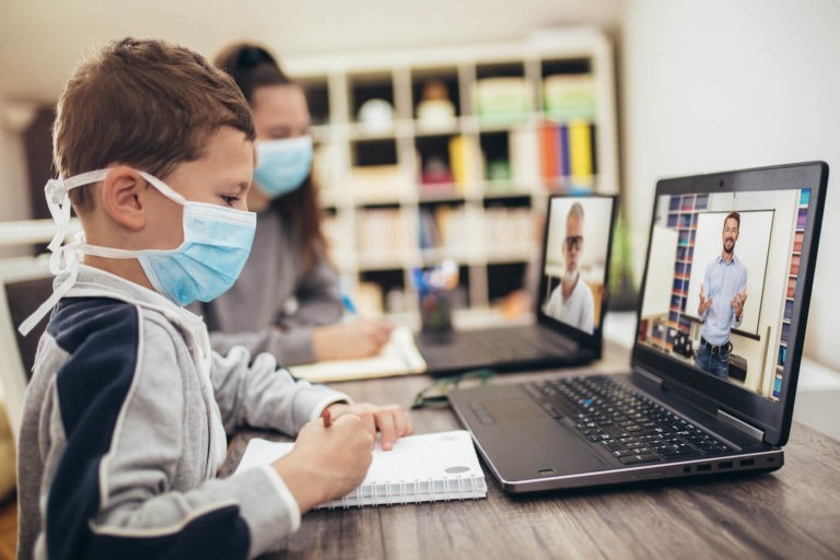 Students wearing masks using computers in a classroom.