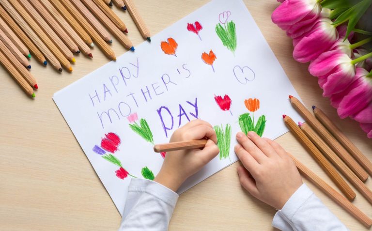 Child drawing a rose on a Mother’s Day Card.