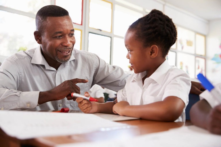 Teacher helping a young girl at her desk.