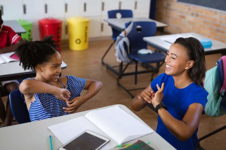 A female teacher and girl talk in sign language at an elementary school.