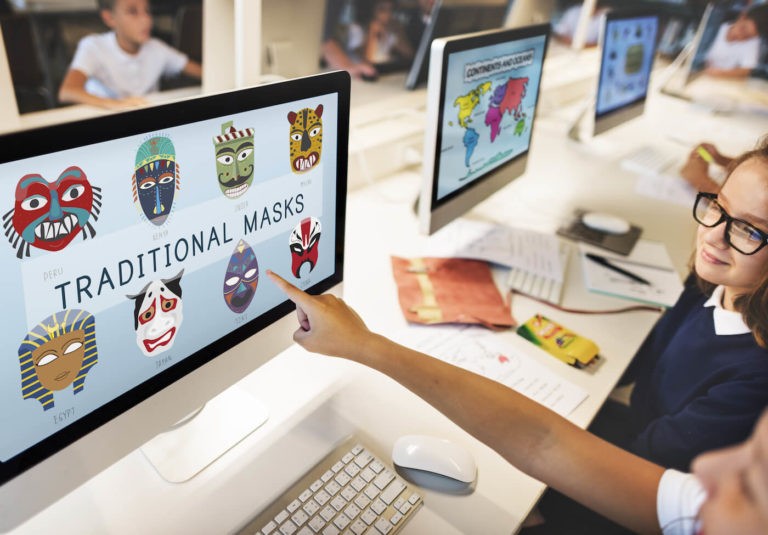 Student pointing to a computer with images of traditional masks.