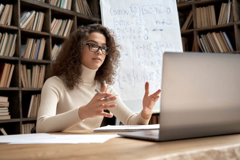 Young math teacher in a library talking during a zoom class.