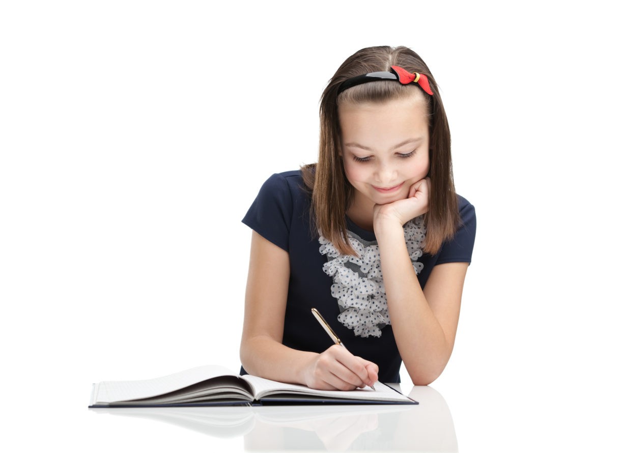 Young girl writing a story in her notebook