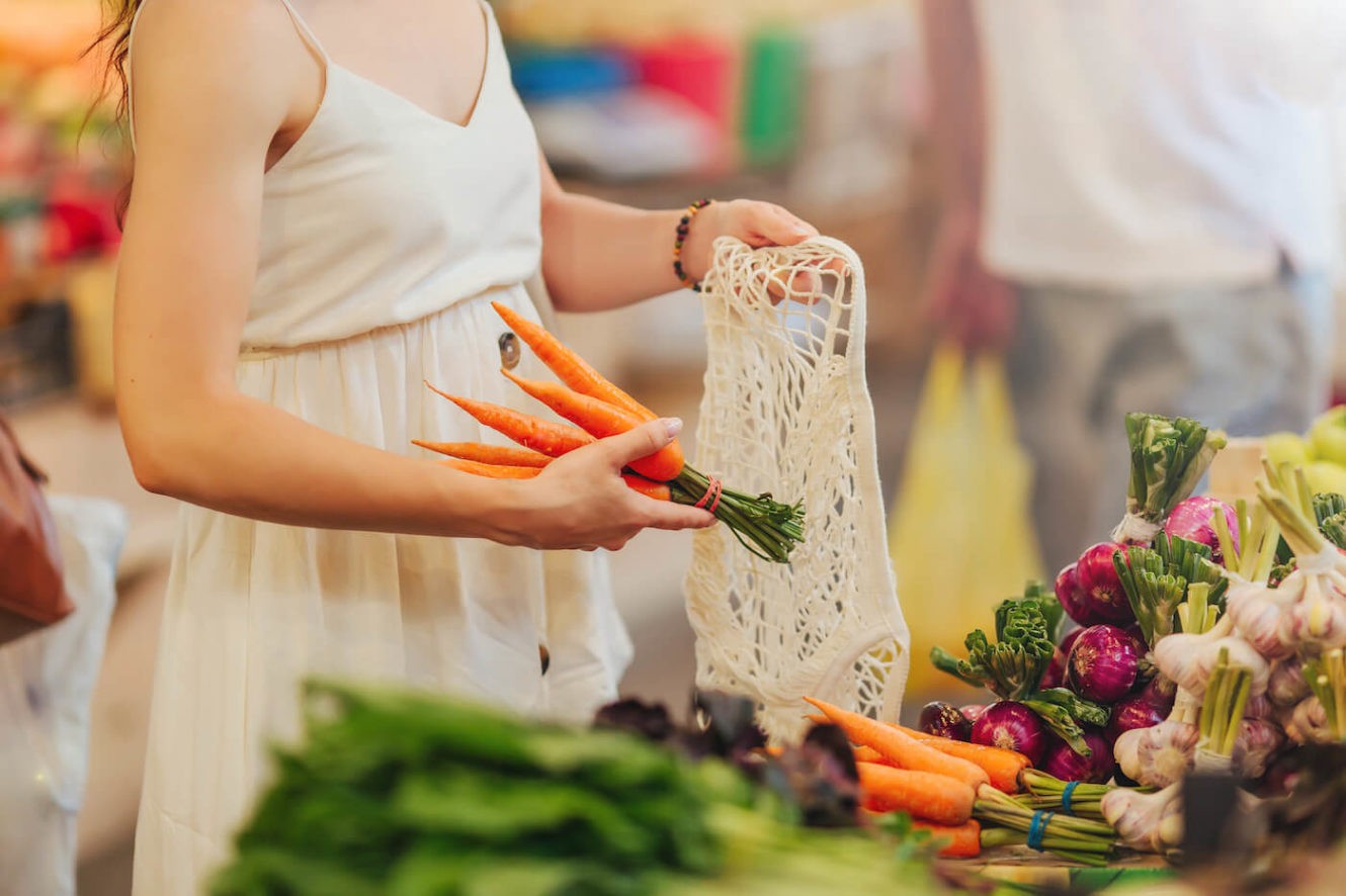 Woman putting carrots in a bag at a grocery store