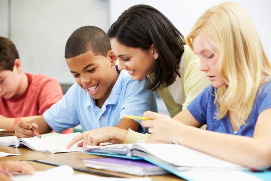 Female teacher helping student with writing assignment