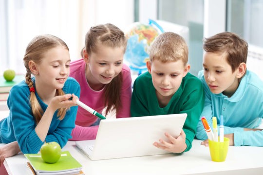 A group of young students working together at a laptop