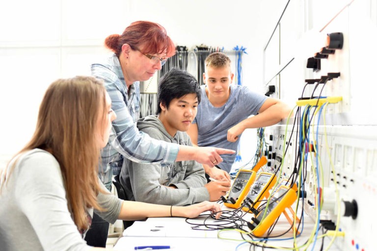 A teacher working with several students in a vocational class.