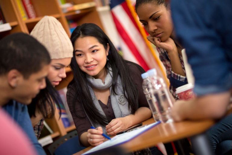 Group of high school students working together at a table in the library.