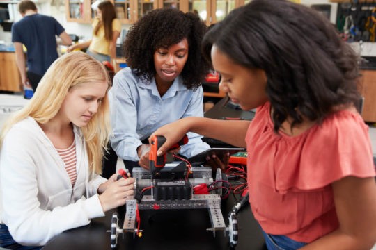 Female high school students working on a robotics project in class.