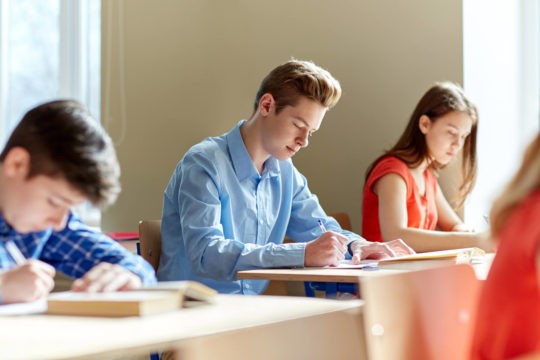 High school students sitting at their desks writing.