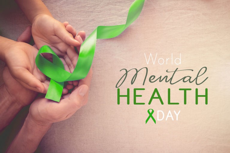 Adult and child hands hold a lime green ribbon next to text reading “World Mental Health Day.”