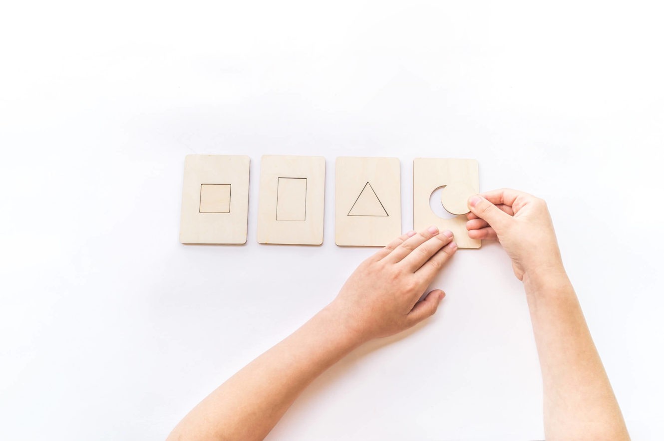 Young student playing with shape pieces