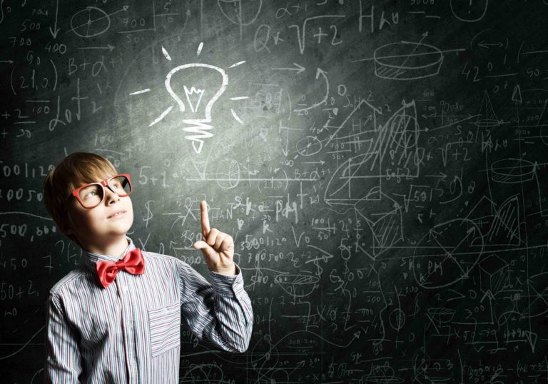 Young boy pointing to a light bulb drawn on a chalkboard