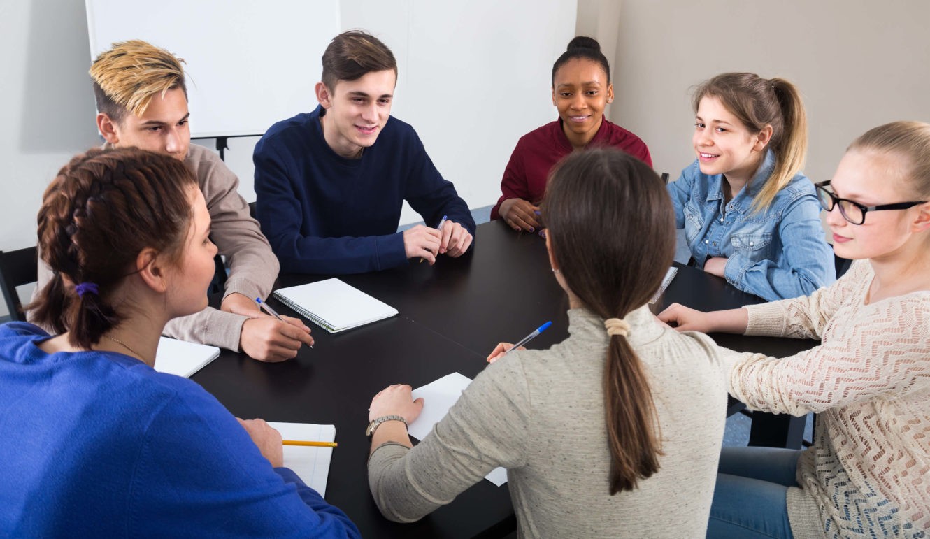 A group of high school students sitting around a circle working together