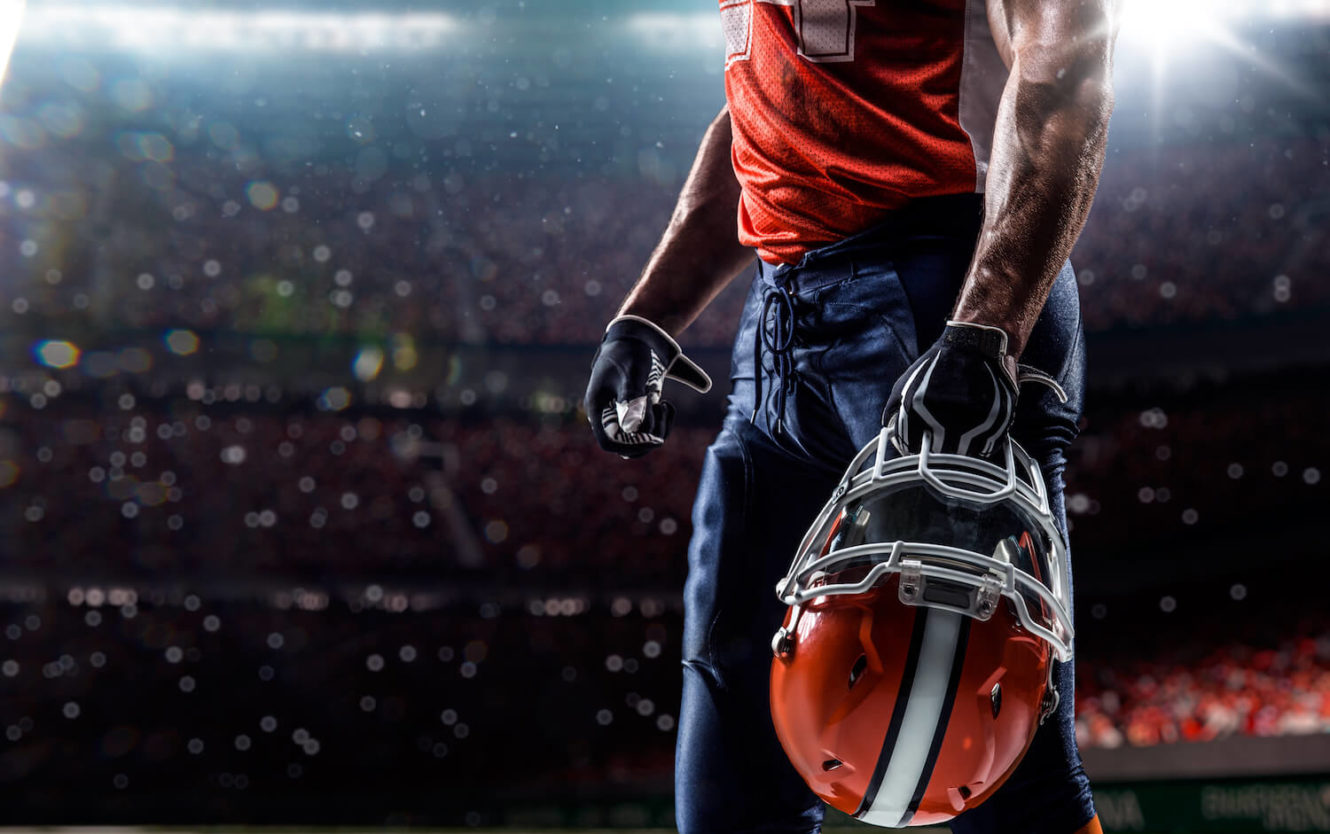 Football player in stadium holding helmet