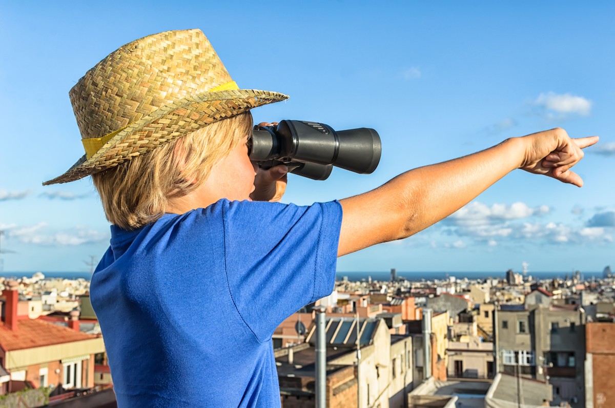 Young boy looking at city with binoculars