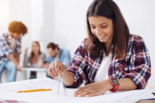 Teenage girl sitting at desk drawing a circle with a protractor