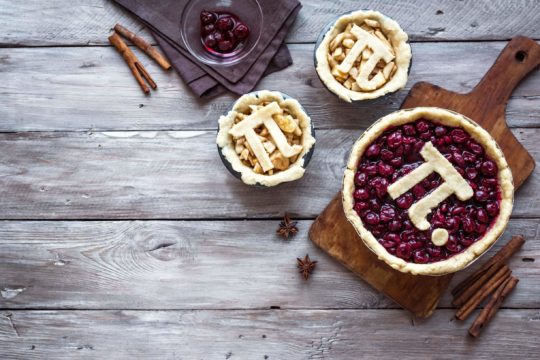 Three pies sitting on a table with the pi sign on top.