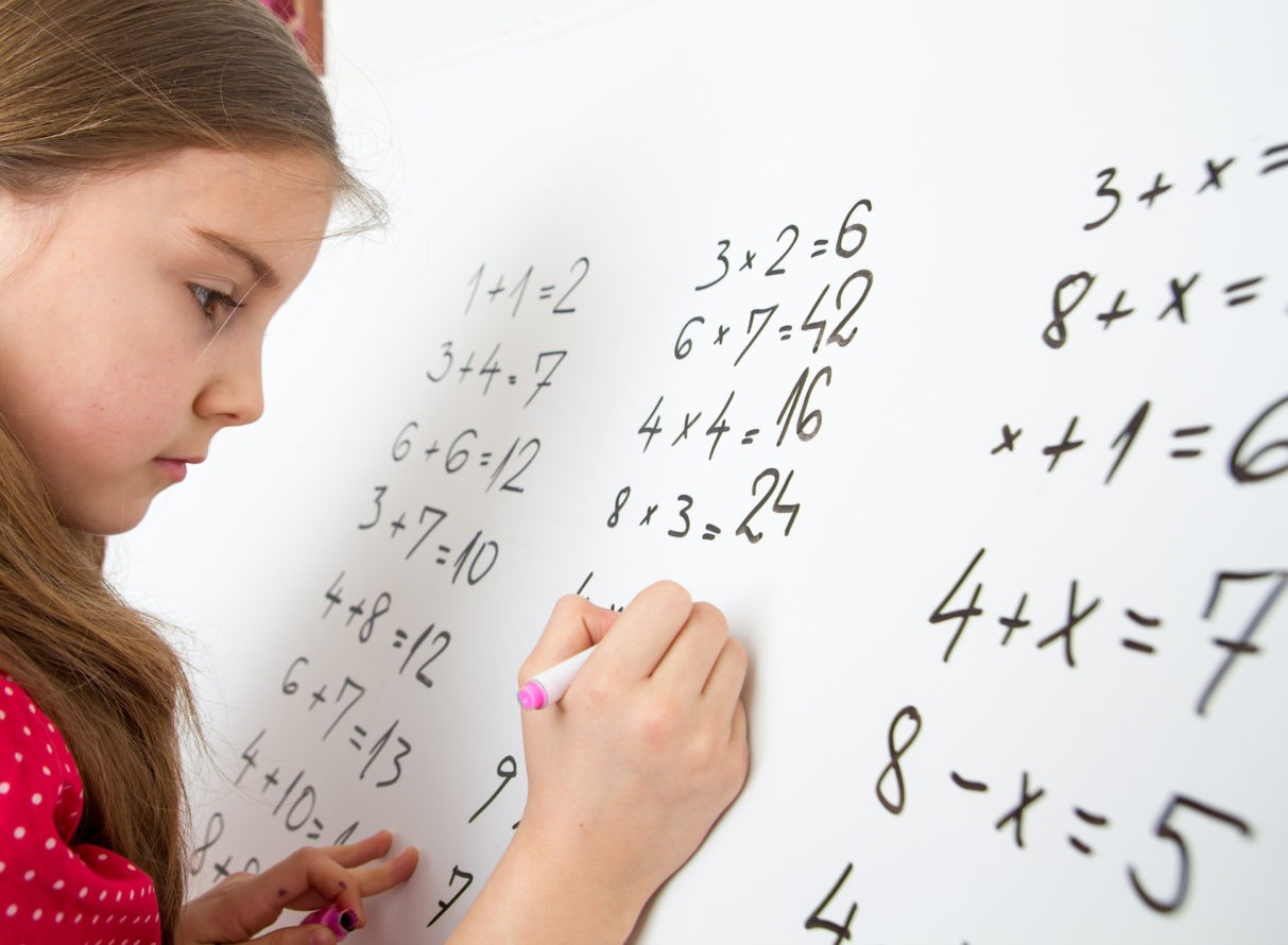 Young girl solving math problems on white board