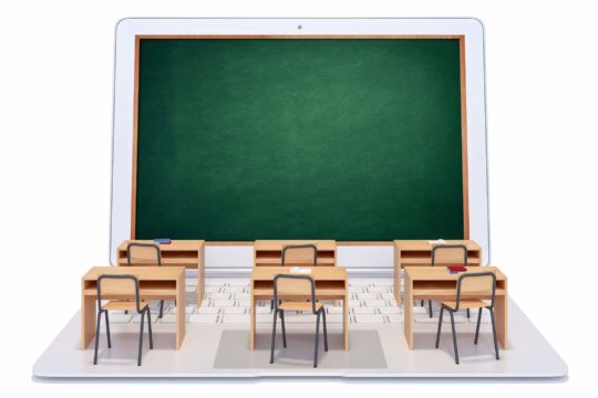 Open laptop with a blackboard as the screen and desks on the keyboard.