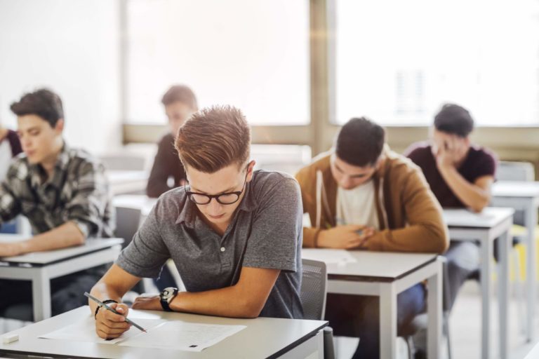 High school students sitting at desks and writing on paper.